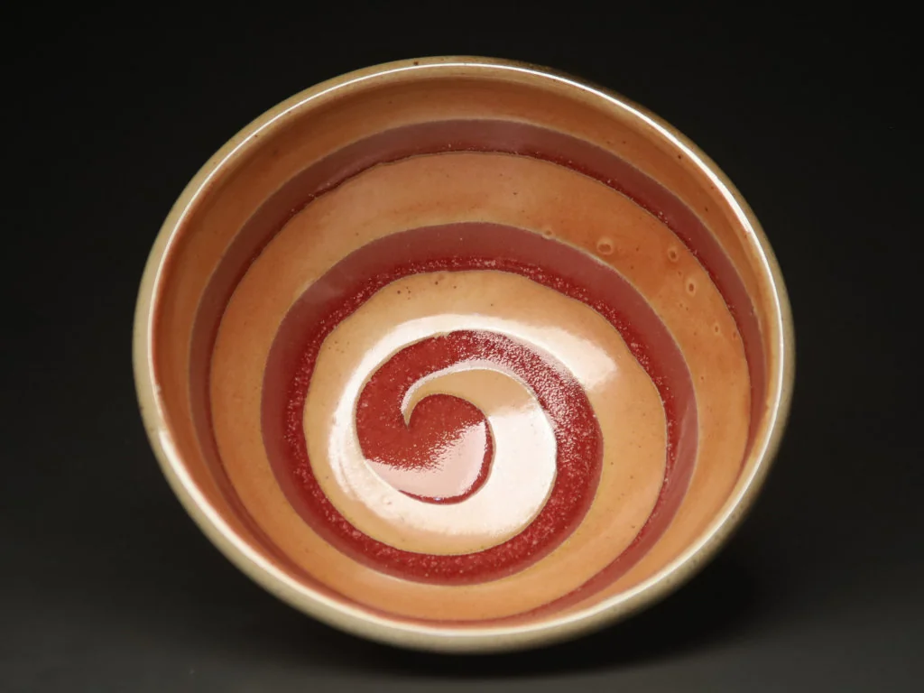 Spiral slip-decorated bowl in warm red and cream